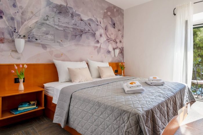 Oslikan zid sa uredno namještenim krevetom i ručnicima za naše goste