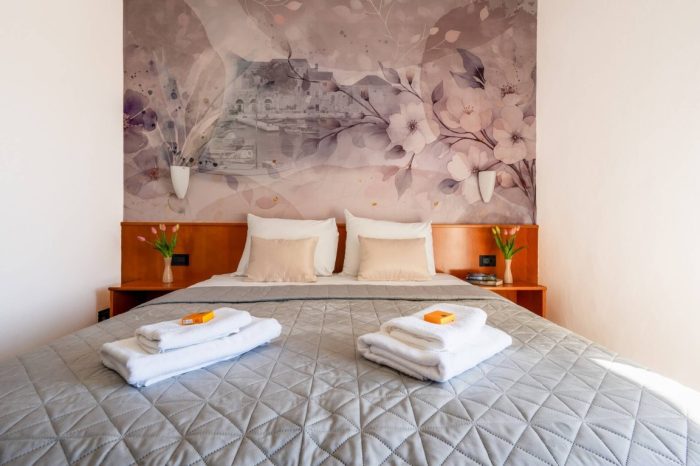 Oslikan zid sa uredno namještenim krevetom i ručnicima za naše goste