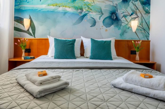 Oslikan zid sa uredno namještenim krevetom i ručnicima za naše goste