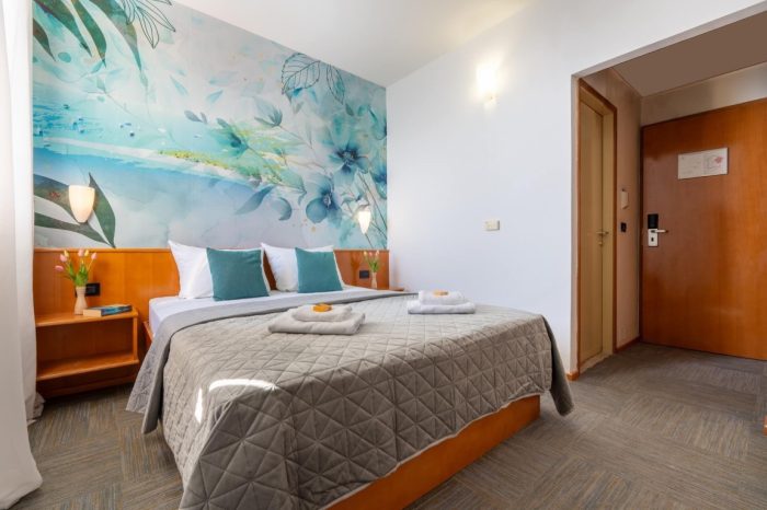 Oslikan zid sa uredno namještenim krevetom i ručnicima za naše goste