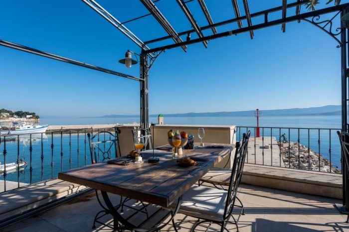 A pleasant arrangement with a bottle of wine on the outdoor terrace surrounded by greenery with a sea view