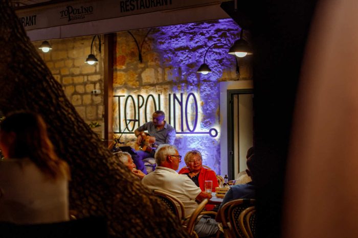 Živa muzika ispod moderne svijetleće reklame restorana zabavlja vjerne goste