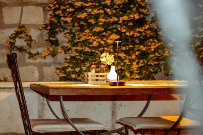 Minimalistički dekoriran drveni stol za dvoje sa cvijetom i lampom